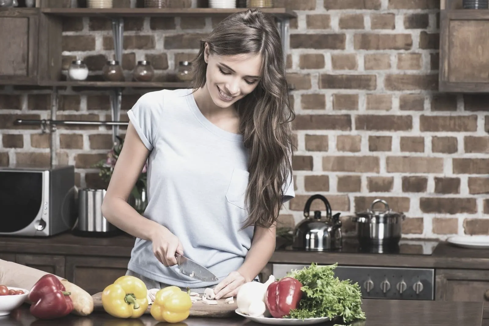woman cooking dinner smiling and happily chopping the vegetables inside the kitchen