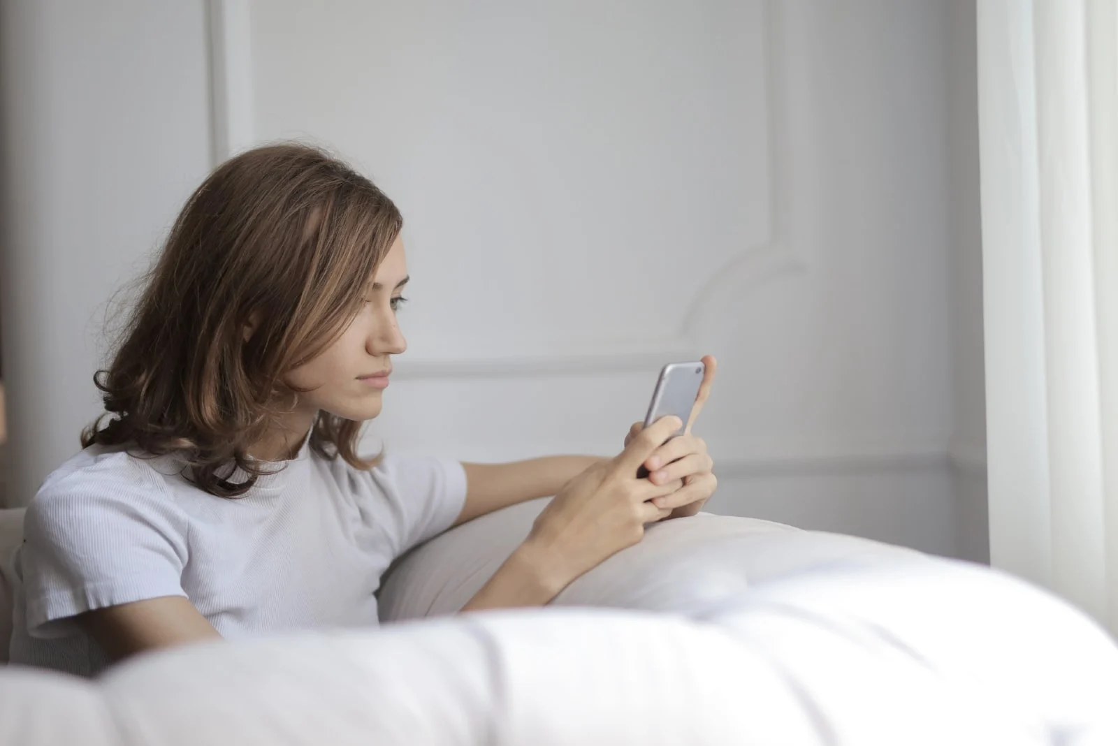 woman holding smartphone while sitting on sofa