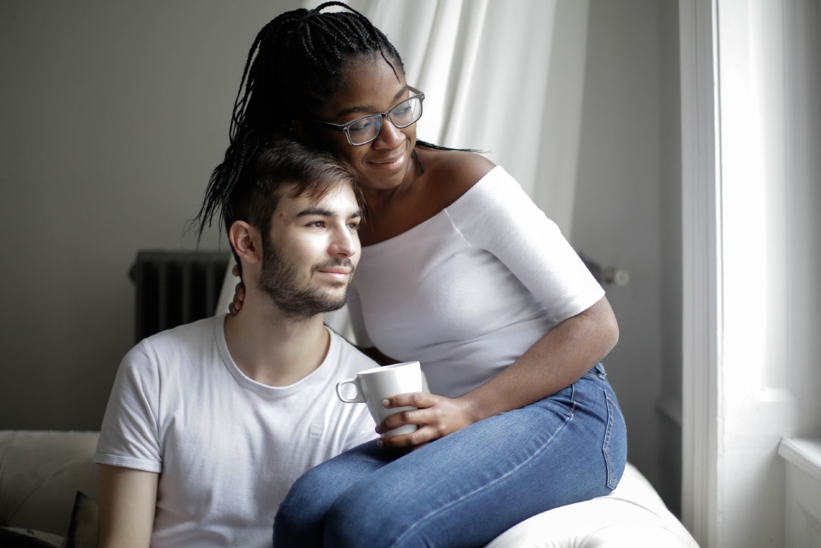 vrouw die een man omhelst terwijl hij op de bank zit