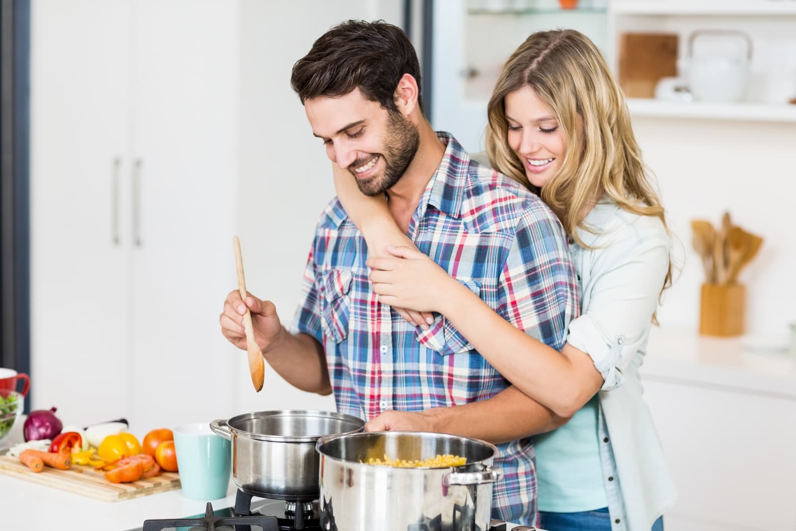 woman hugging man while standing in the kitchen