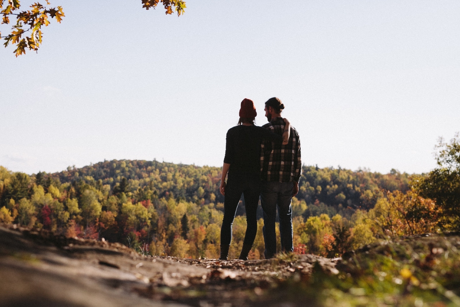 woman hugging man while standing near green grass field