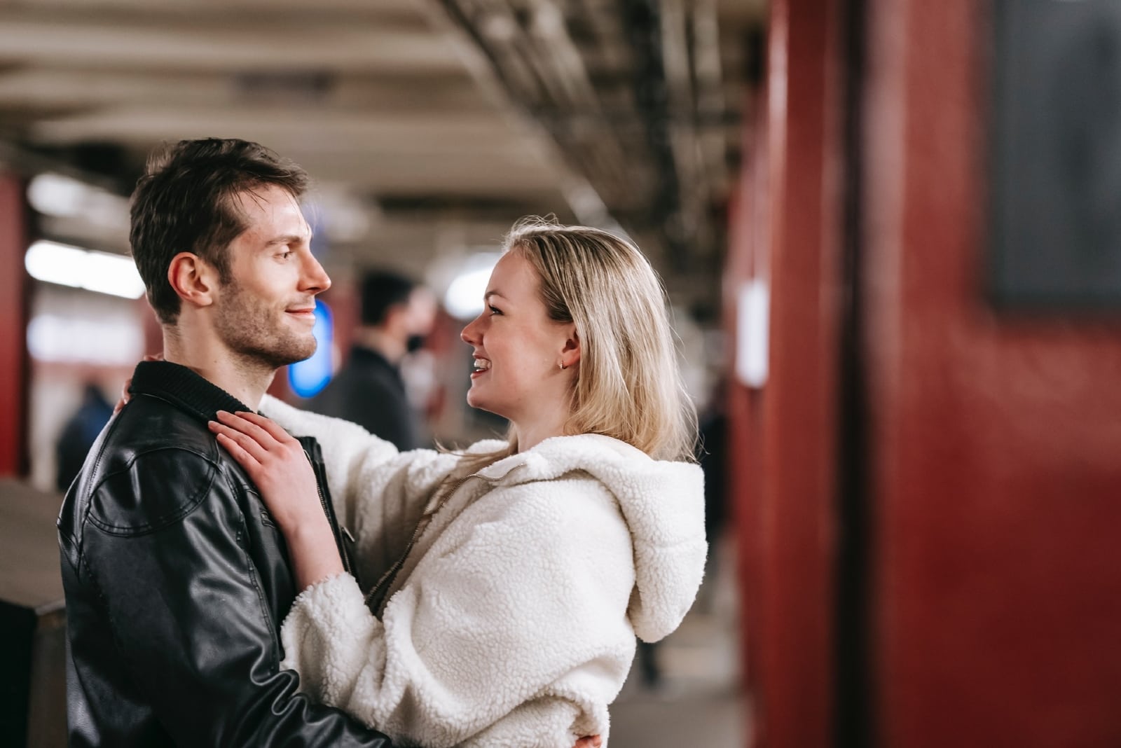 donna con giacca bianca che abbraccia un uomo all'aperto