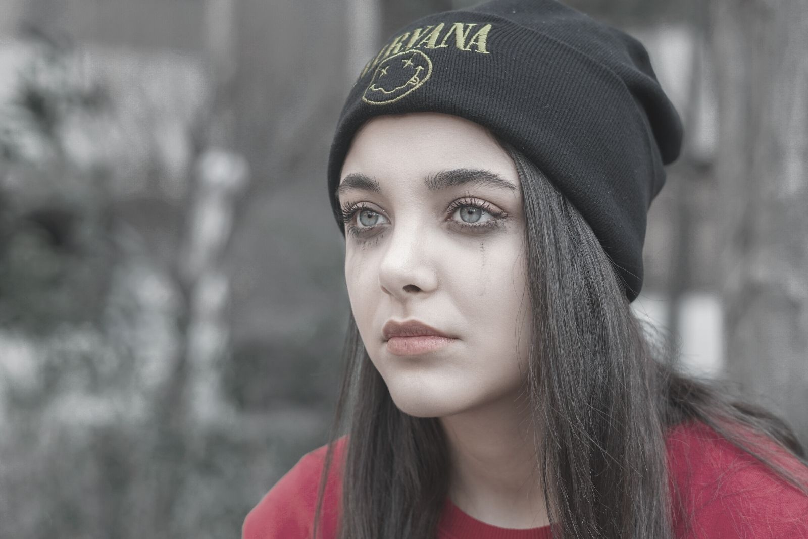 mujer con gorro de punto negro llorando con gota de maquillaje negro