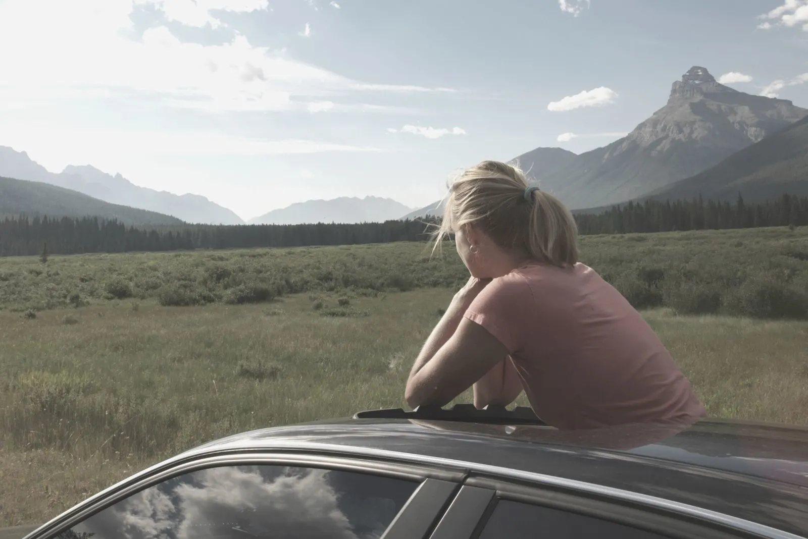 woman in the car looking outside in the meadow