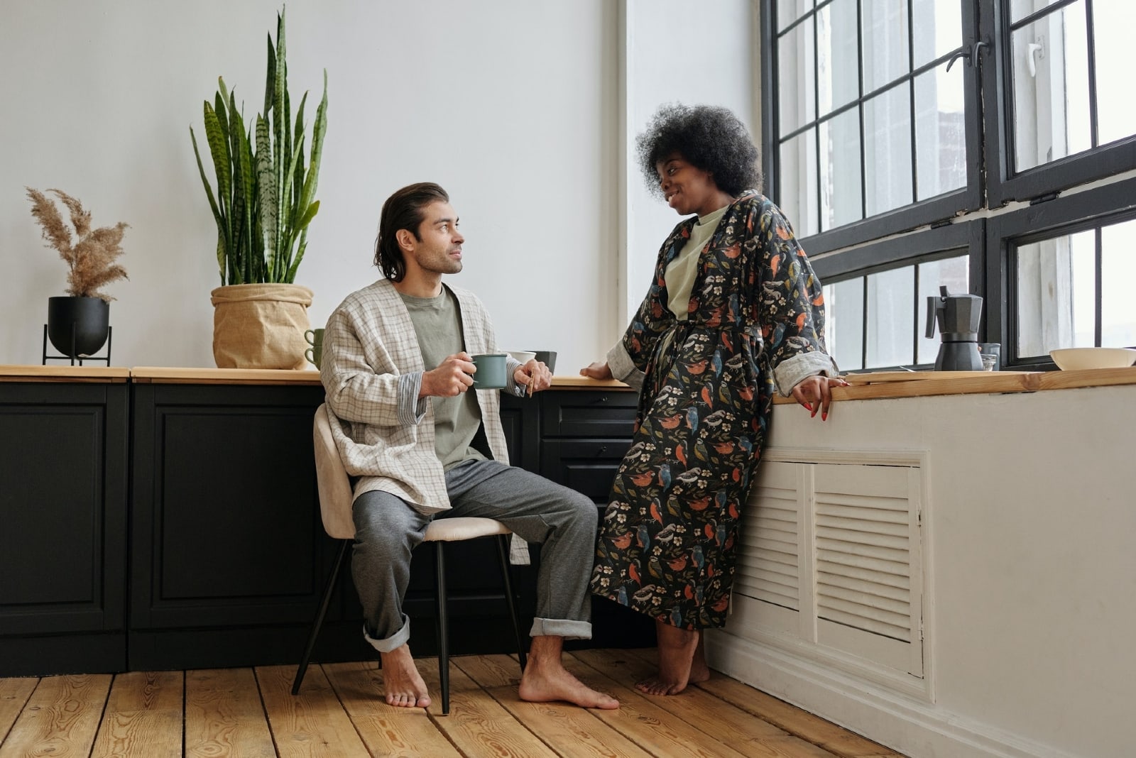 woman looking at man while standing near window