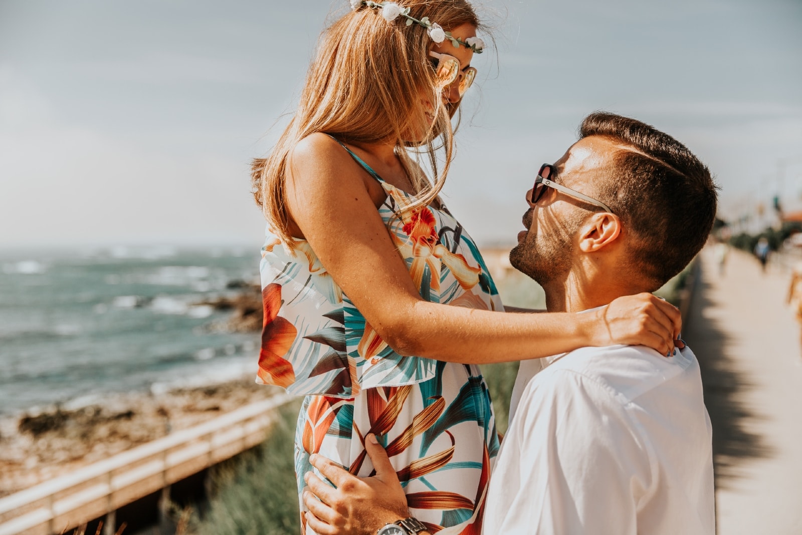  lycklig kvinna i lång blommig klänning som tittar på mannen