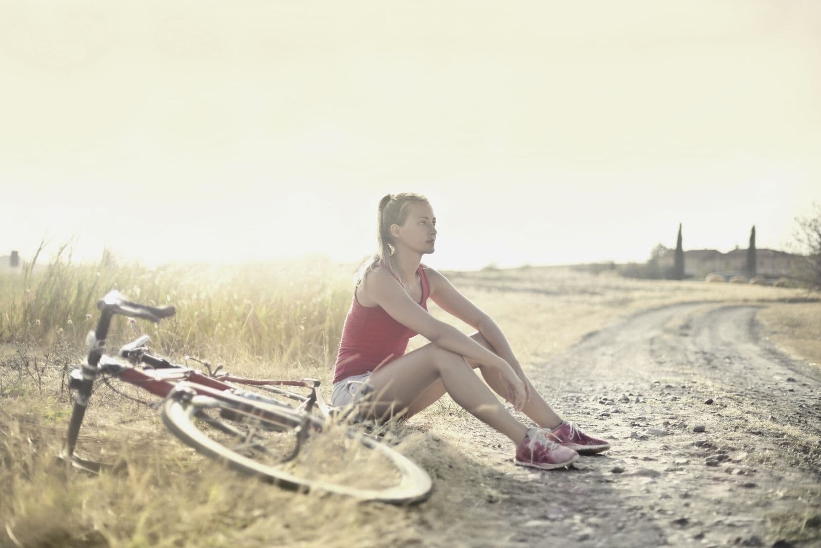 woman on dirtbike resting on the side on an open field of the country