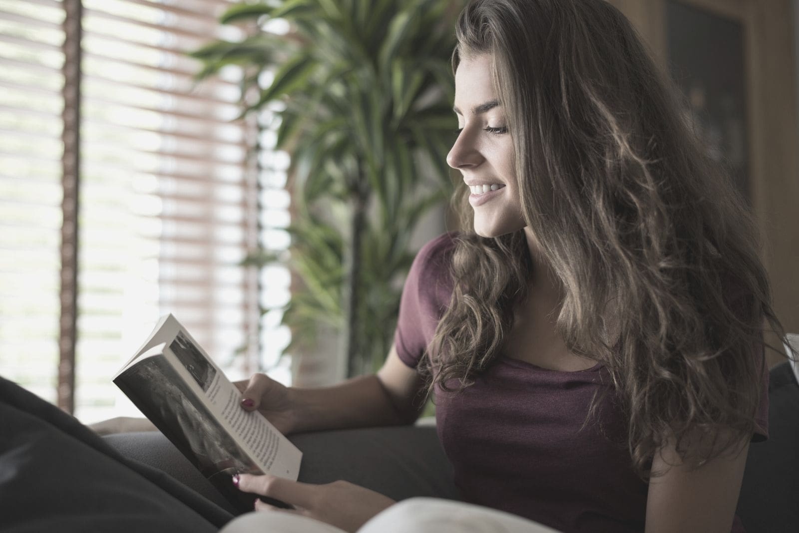 mujer leyendo un libro y sonriendo mientras se relaja y lee un libro 