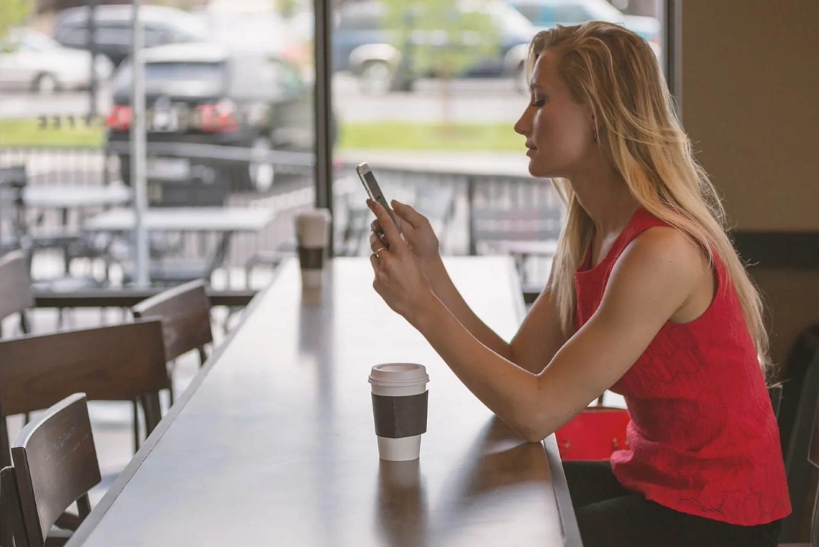 blonde woman sitting at table looking at phone