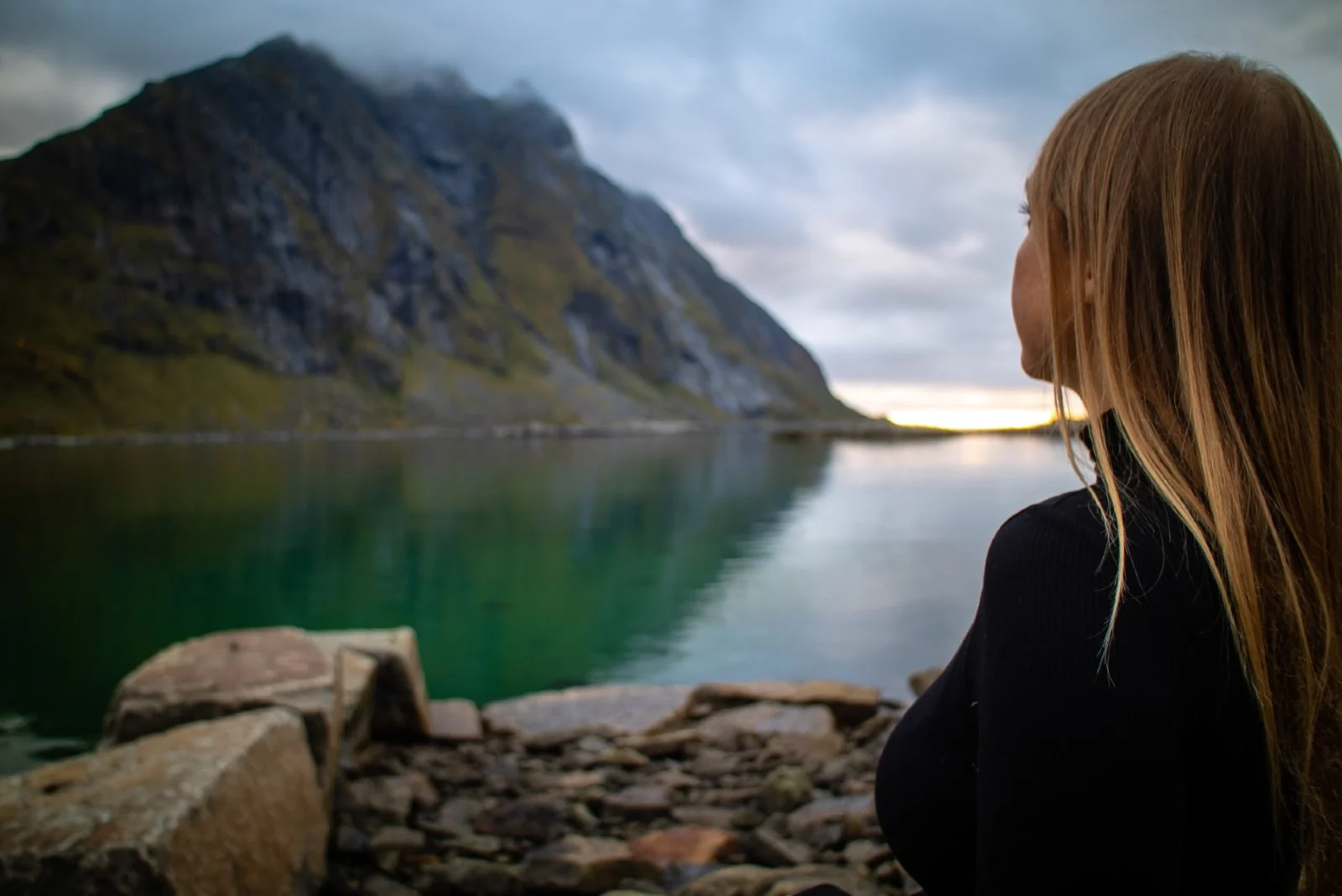 woman in black turtleneck sweater sitting near lake