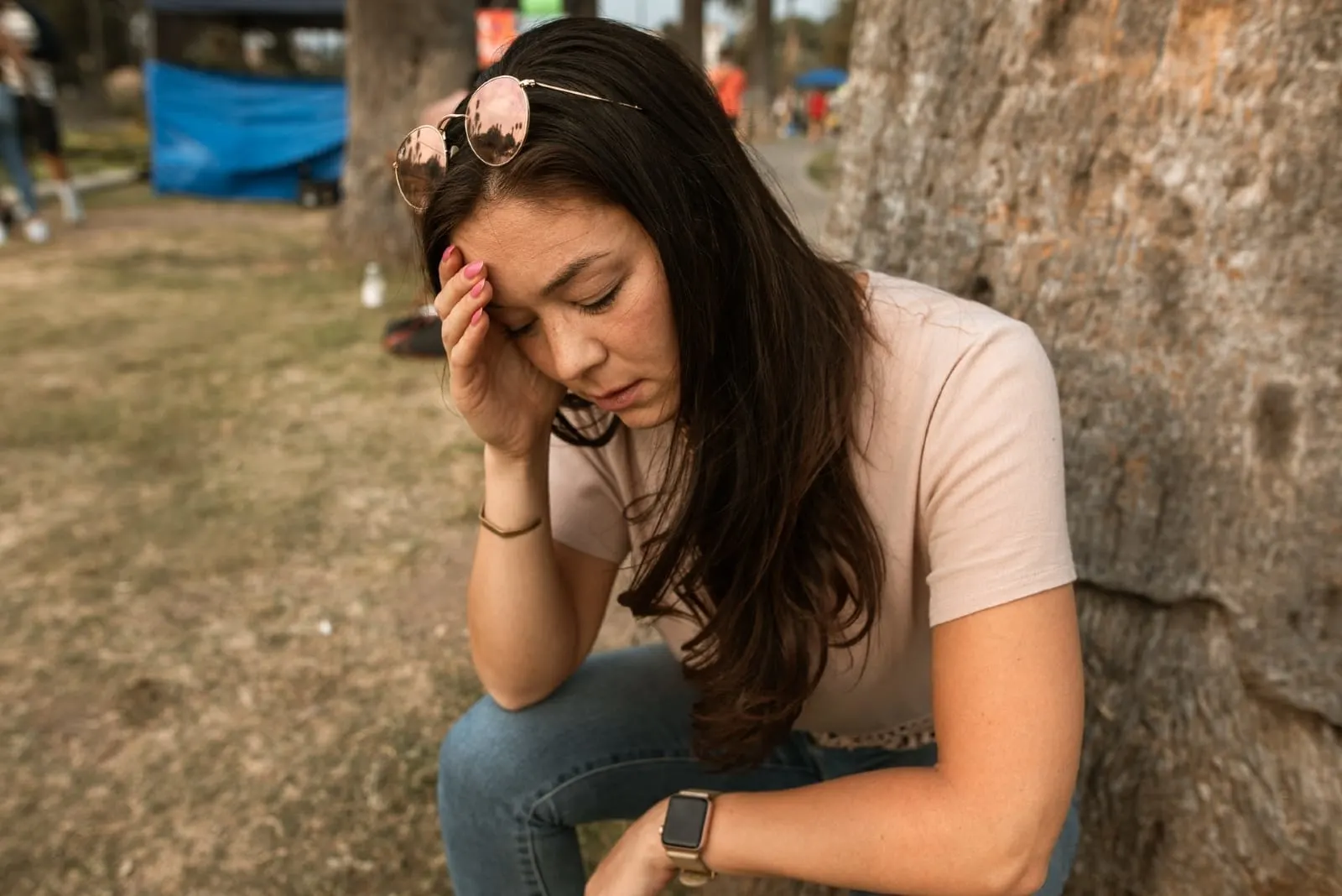 worried woman in white t-shirt sitting near tree