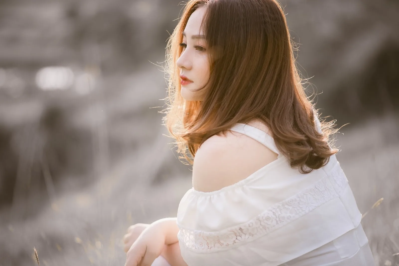 sad woman in white top sitting outdoor