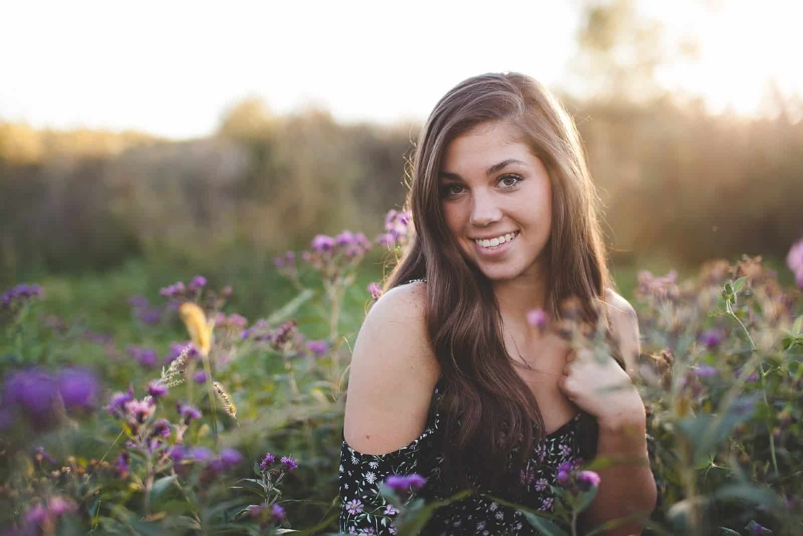 happy woman standing near purple flowers