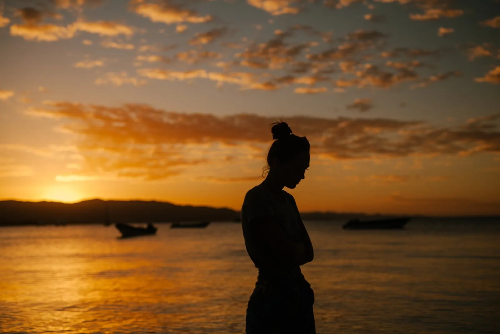 sad woman standing near sea during sunset