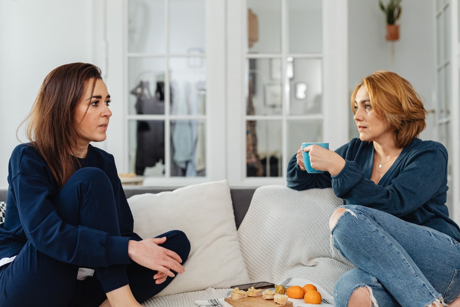 woman talking to woman while sitting on sofa