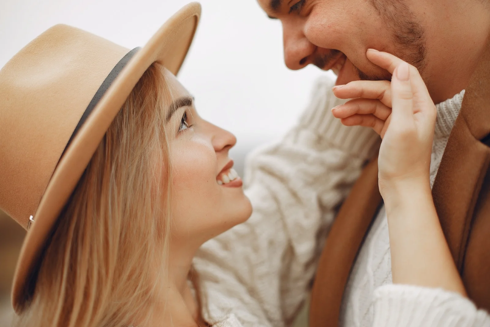 woman with brown hat touching man's face