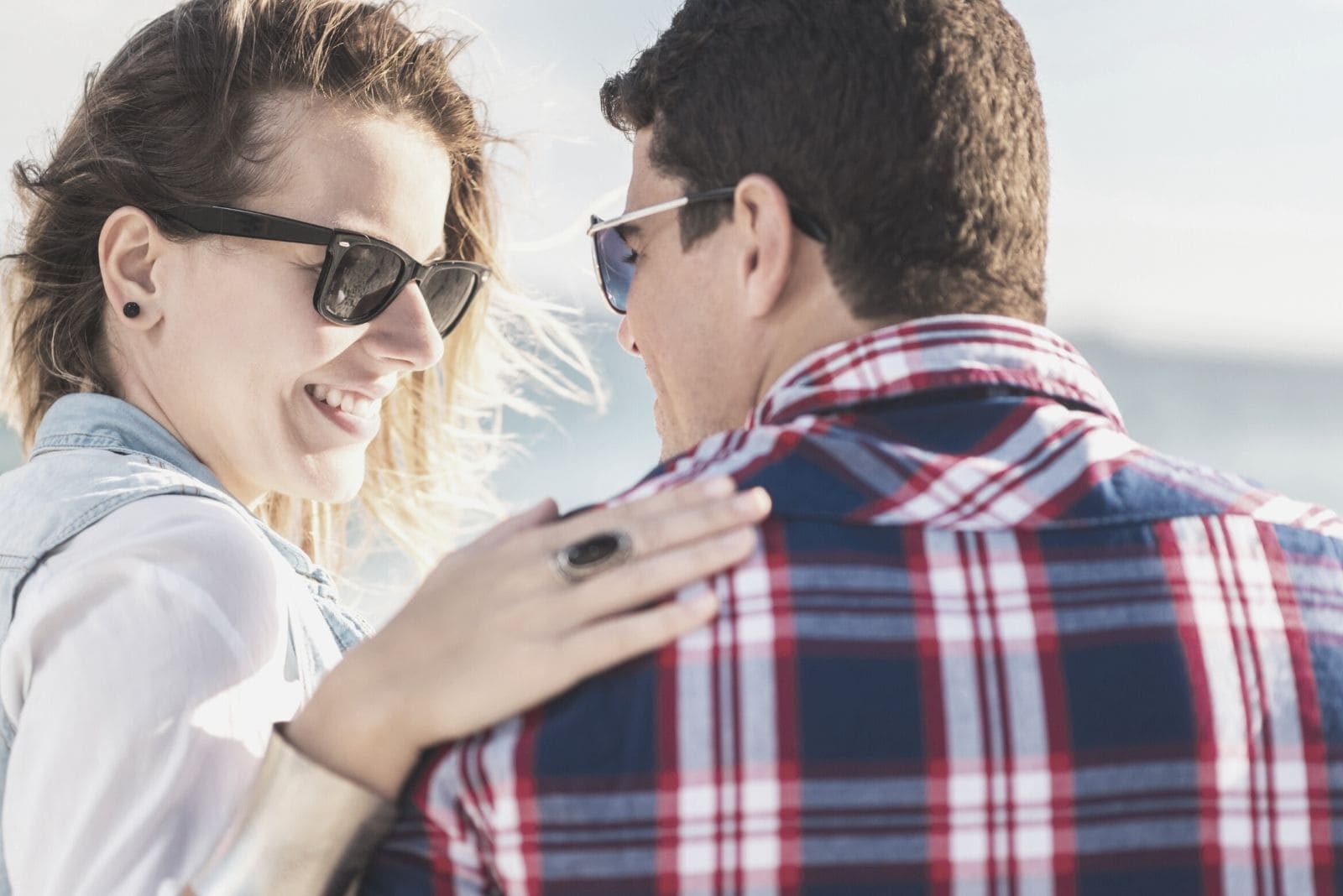 woman touching the shoulders of a man sitting in rear view while talking outdoors