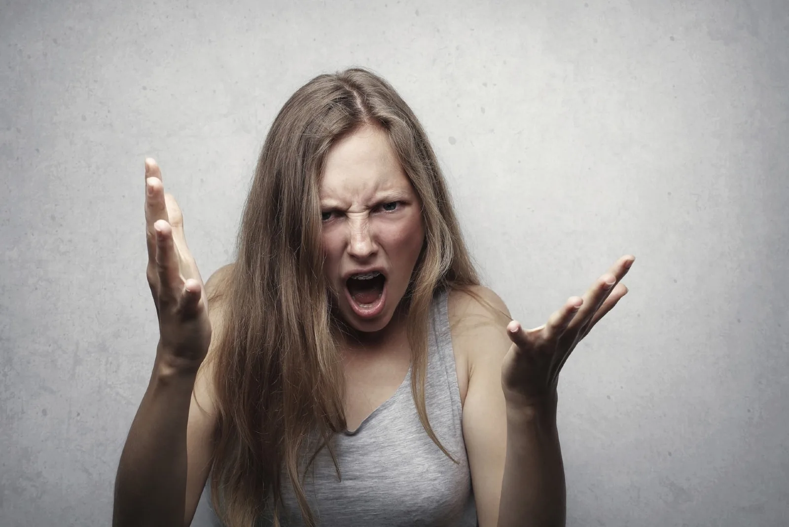 angry woman yelling while standing near wall