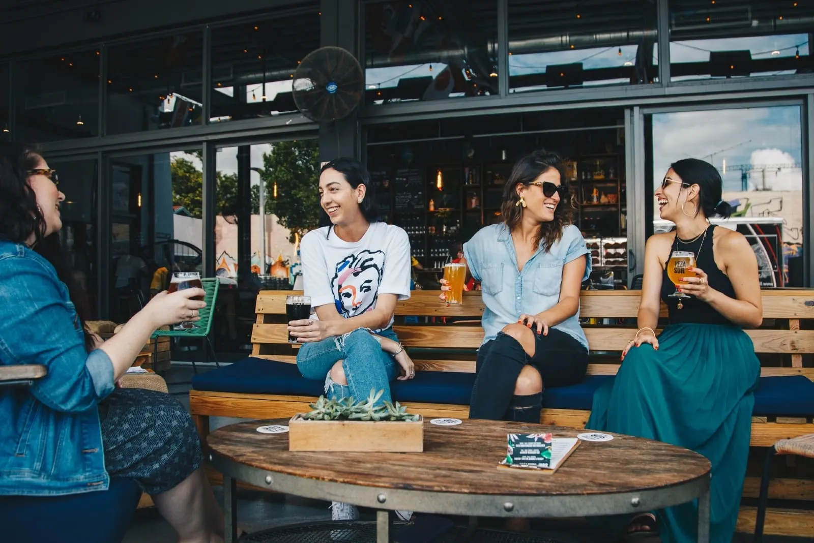 four women smiling while drinking beer outdoor