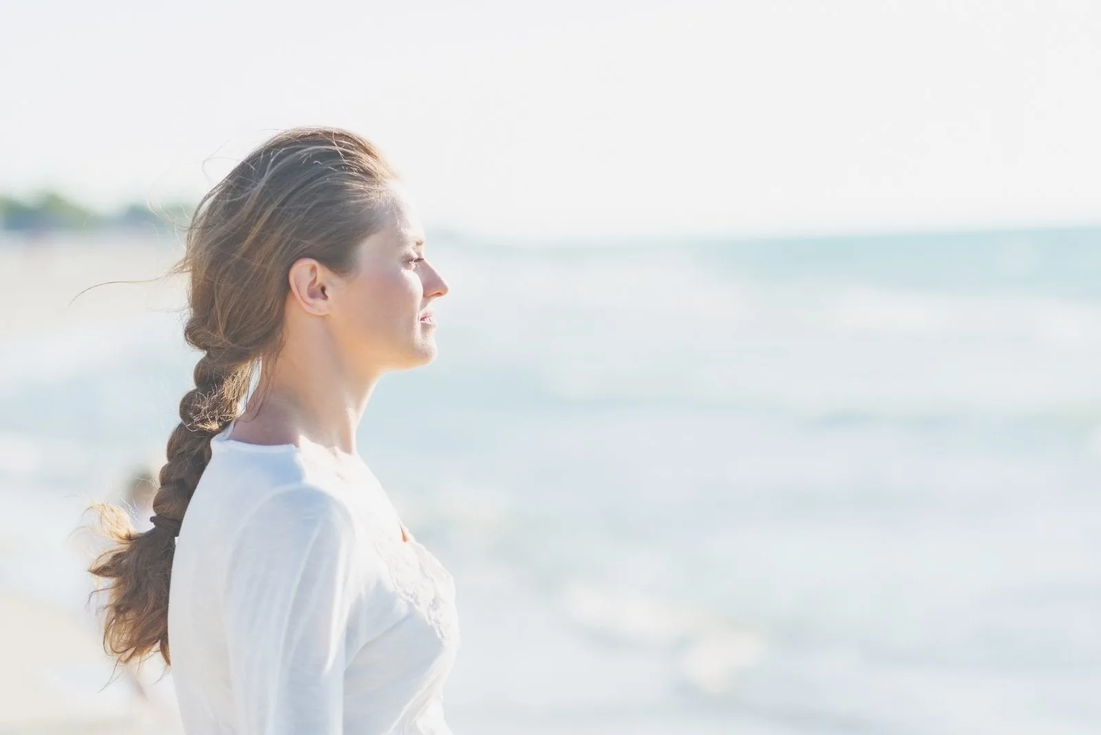 young calm woman standing near the sea and closing eyes