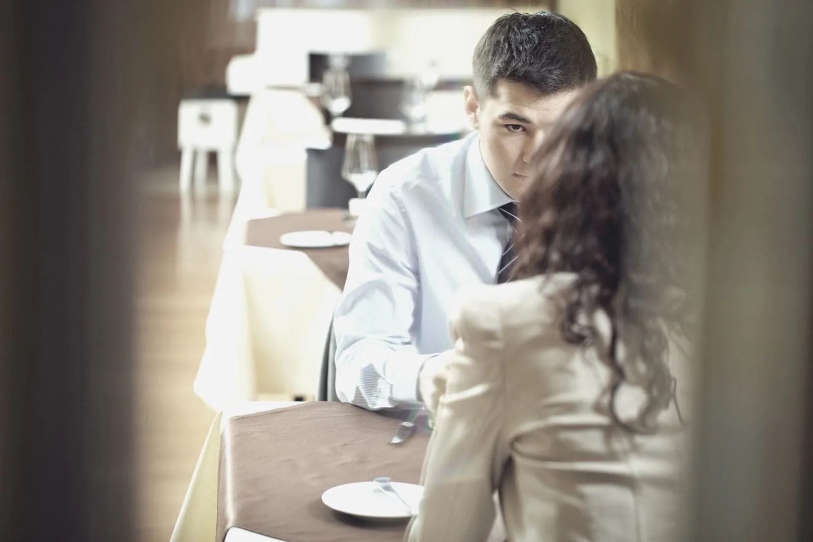 young couple sitting inside the restaurant talking seriously