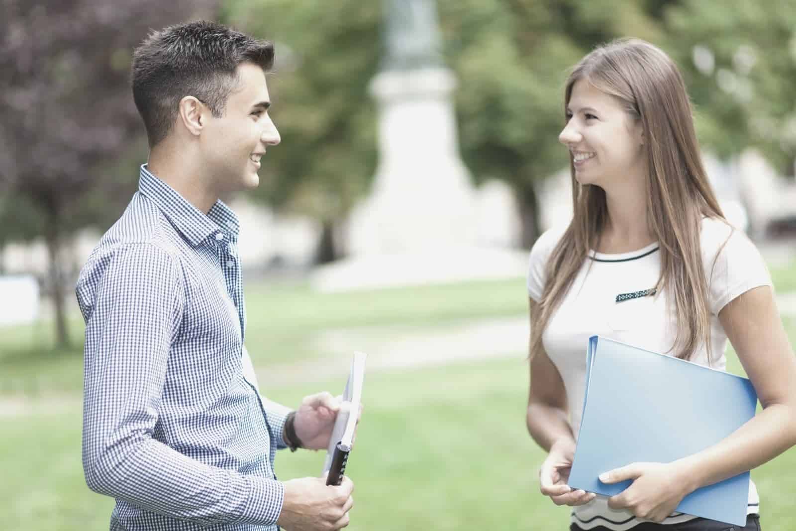 young couple talking outdoors standing in the field of the school