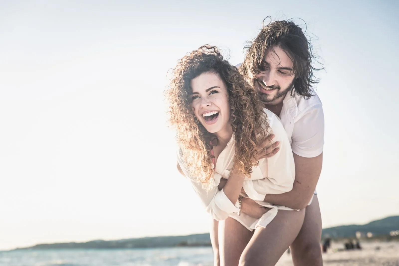 young happy couple hugging and laughing in the beach