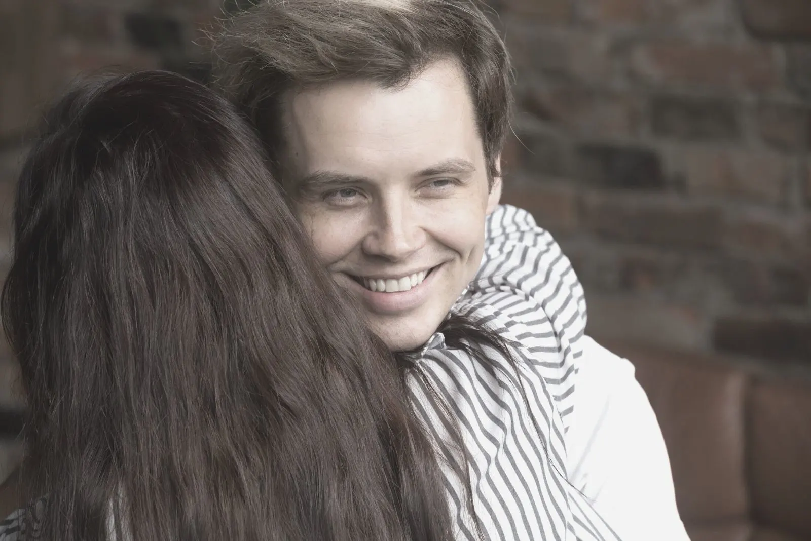 young sly liar man happily smiling embraced by a woman