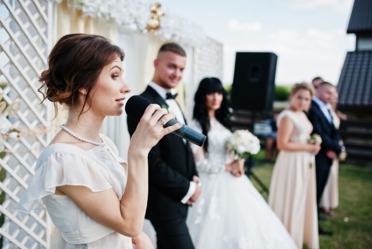 woman talking on microphone while standing near groom and bride