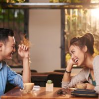 man and woman laughing while sitting at table