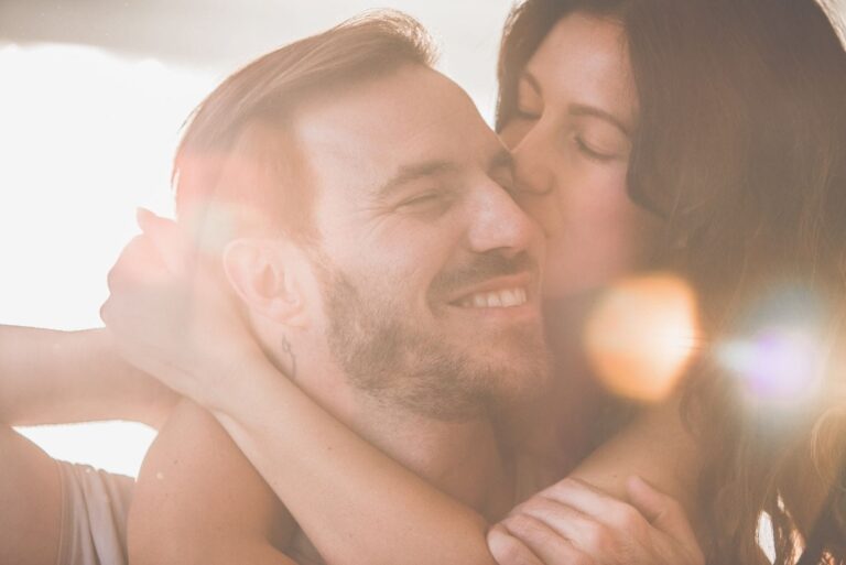 woman kissing and hugging her happy and smiling boyfriend in close up image