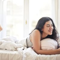 mujer usando smartphone tumbada en la cama