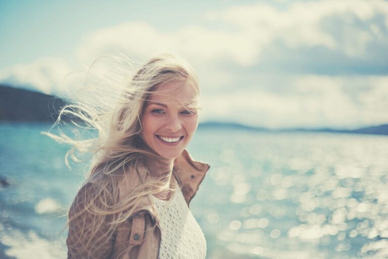 beautiful woman smiling and walking on the beach looking at the camera