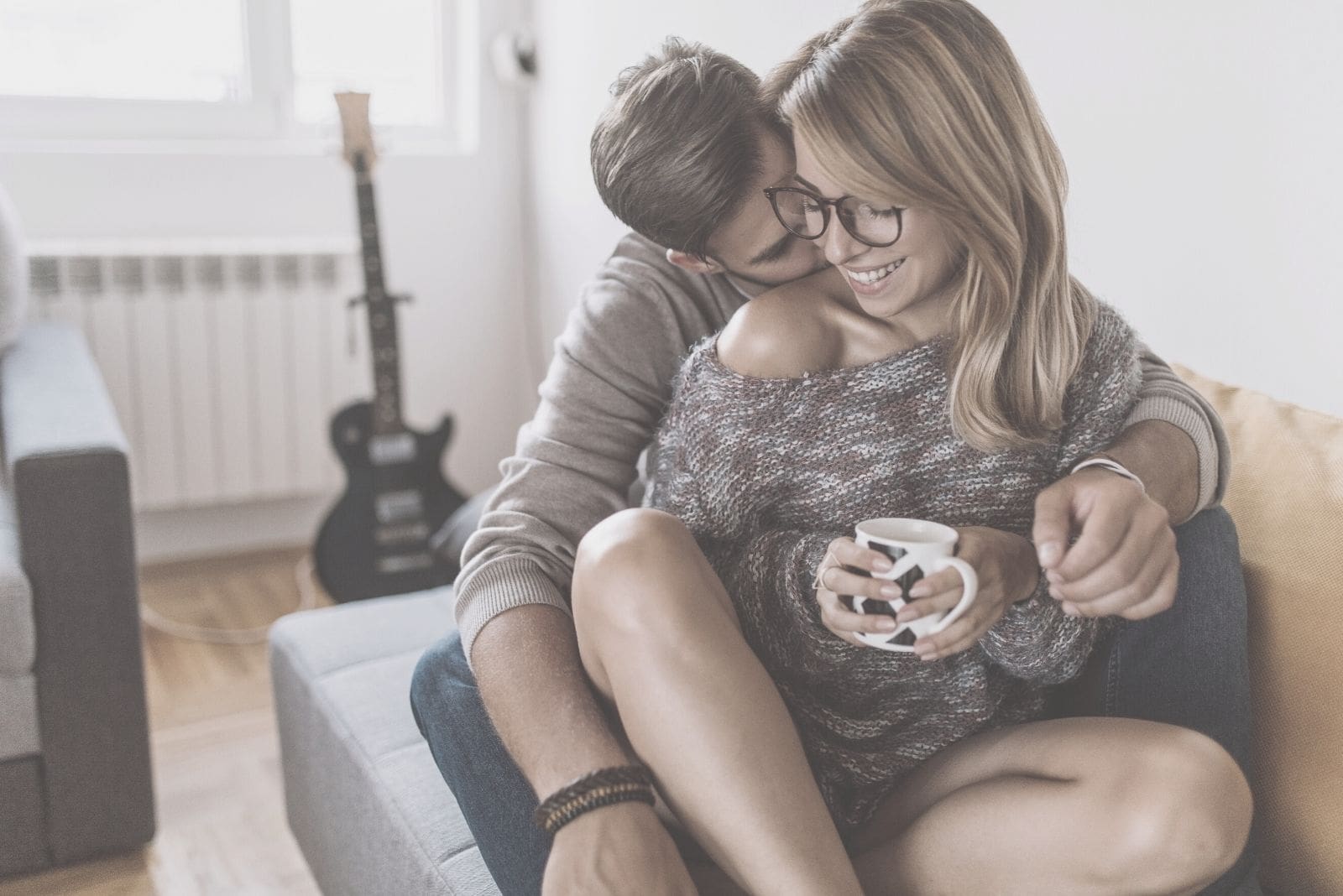 flirty couple hugging inside the livingroom while drinking coffee