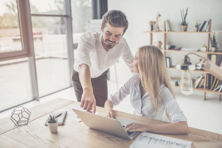 man teaching his female colleague pointing out on the laptop