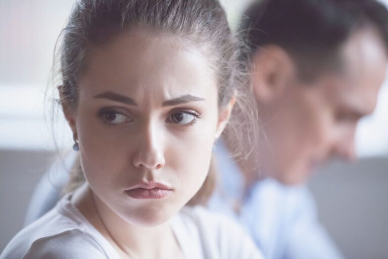 upset woman sitting beside her indifferent husband inside the living room