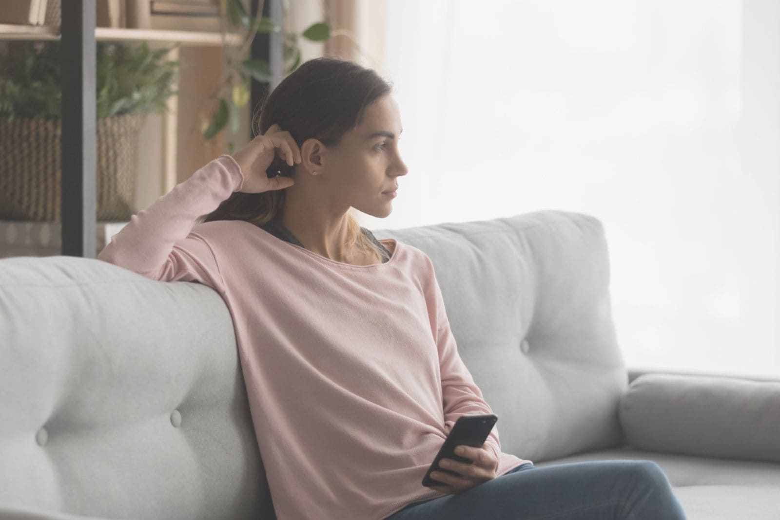 woman waiting and sitting at the sofa holding a smartphone at home