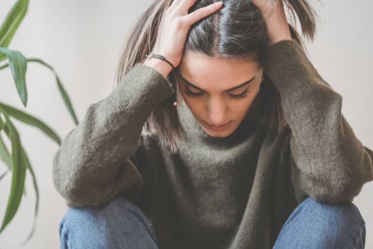sad and depressed young woman sitting on the floor holding on her head down