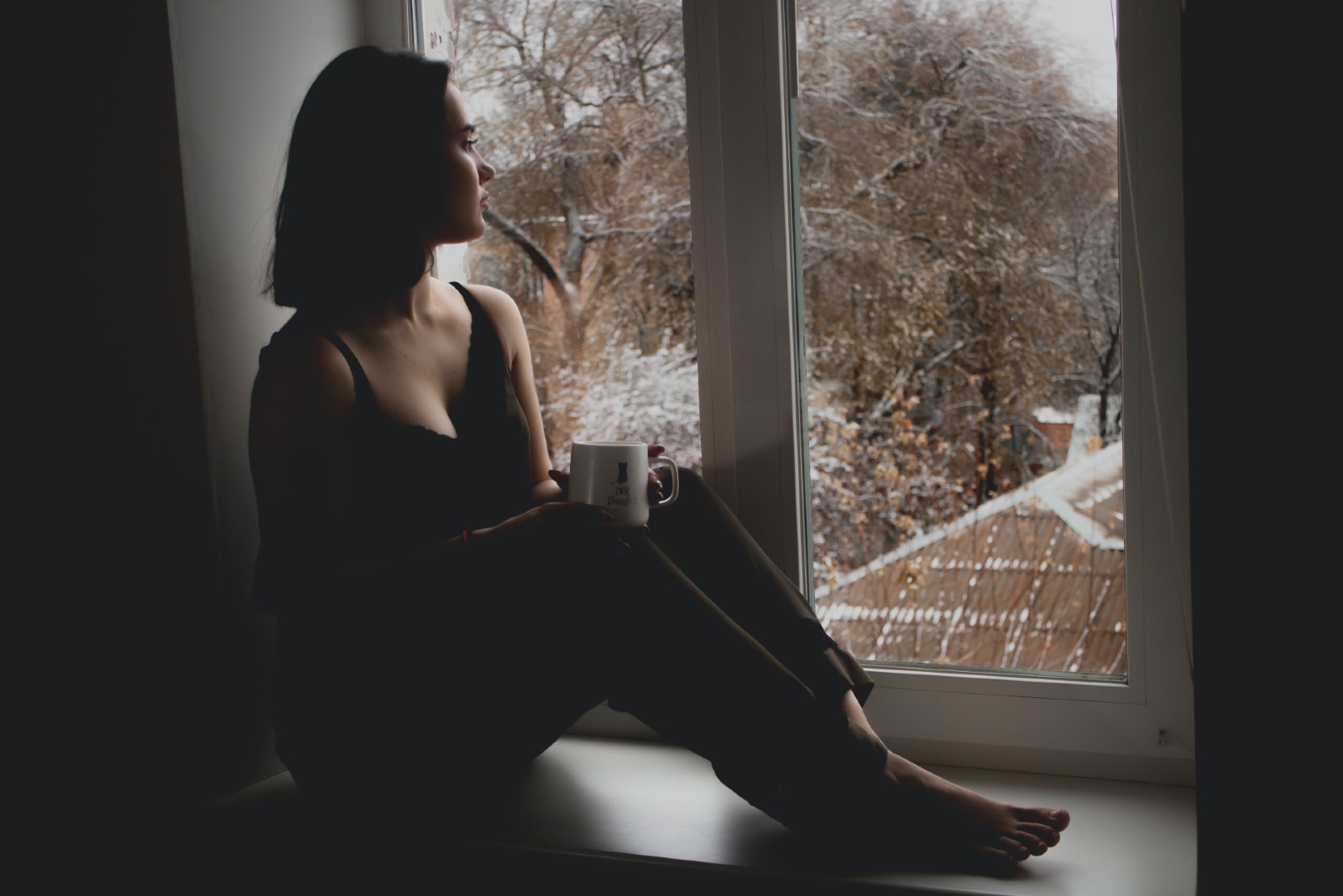 woman sitting on window pane looking through window