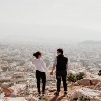 man and woman holding hands while standing on top of hill