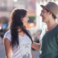 man and woman smiling while standing on the street