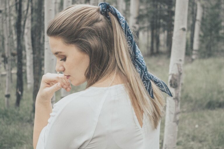 woman showing her back standing in the middle of the woods with kept blonde hair standing pensively