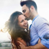 man in blue shirt kissing woman outdoor