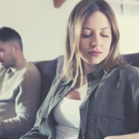 silent and indifferent couple sitting next to each other in the sofa inside living room