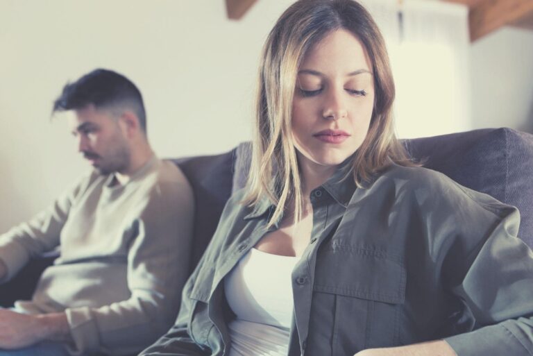silent and indifferent couple sitting next to each other in the sofa inside living room