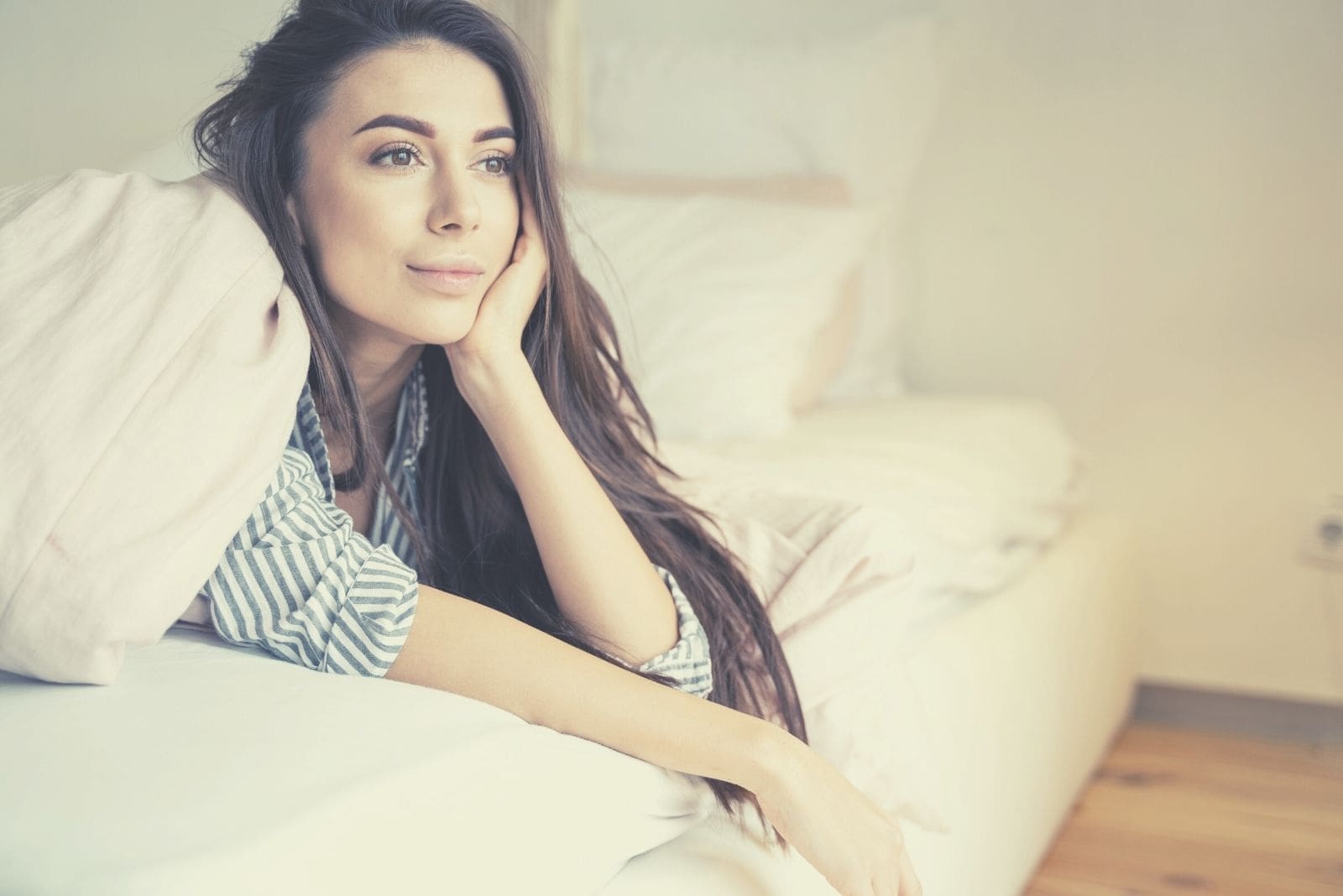 dreamy woman lying in bed looking in front of her