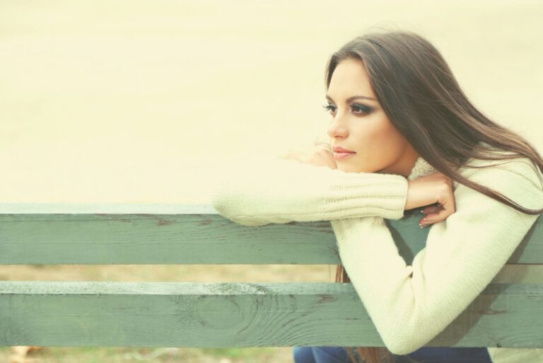 woman sitting on the bench outdoors leaning looking far