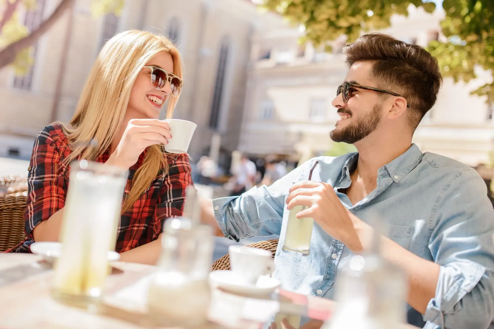 a man and a woman sit at a table and laugh while drinking coffee