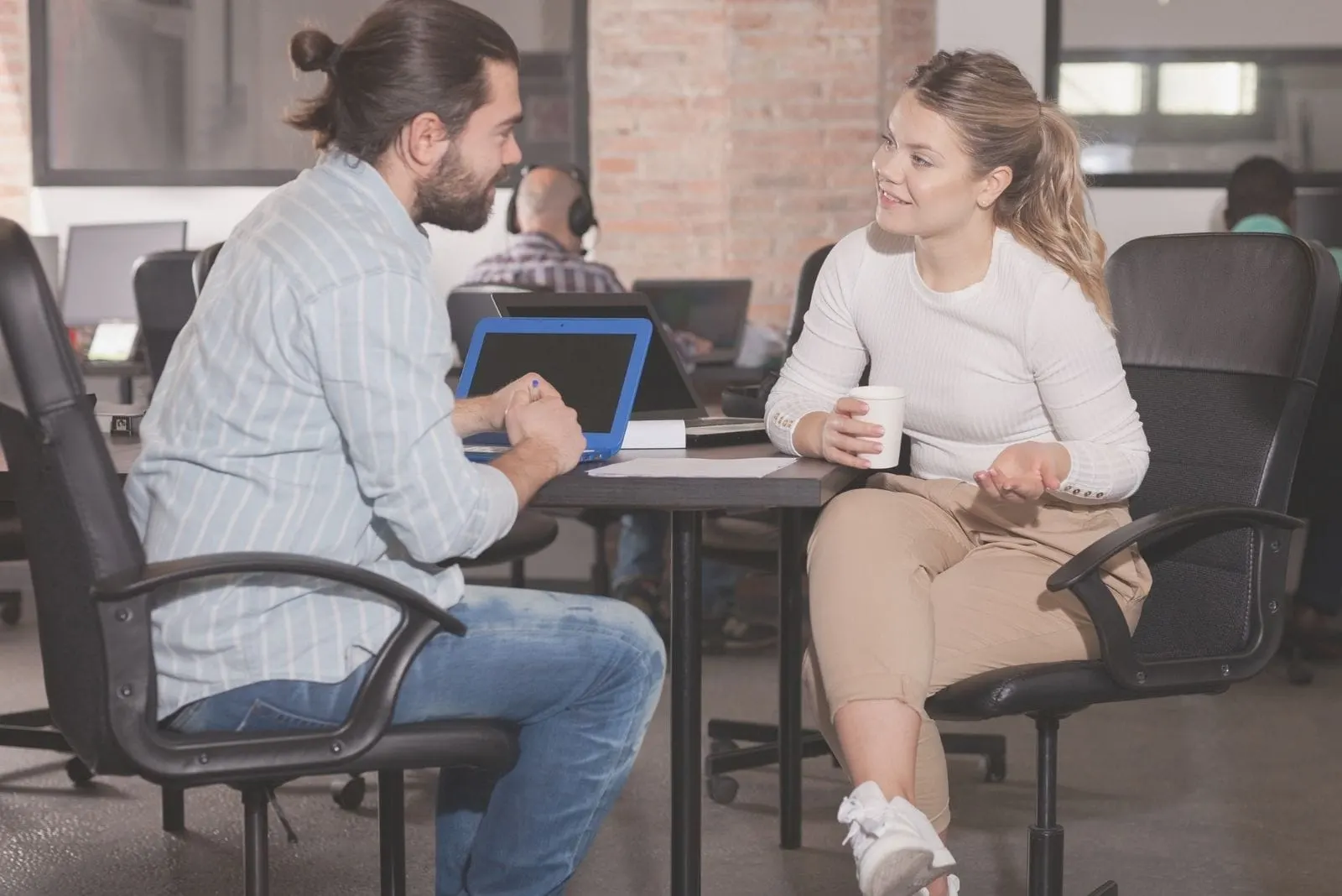 a man and woman talking in the office while having coffee break