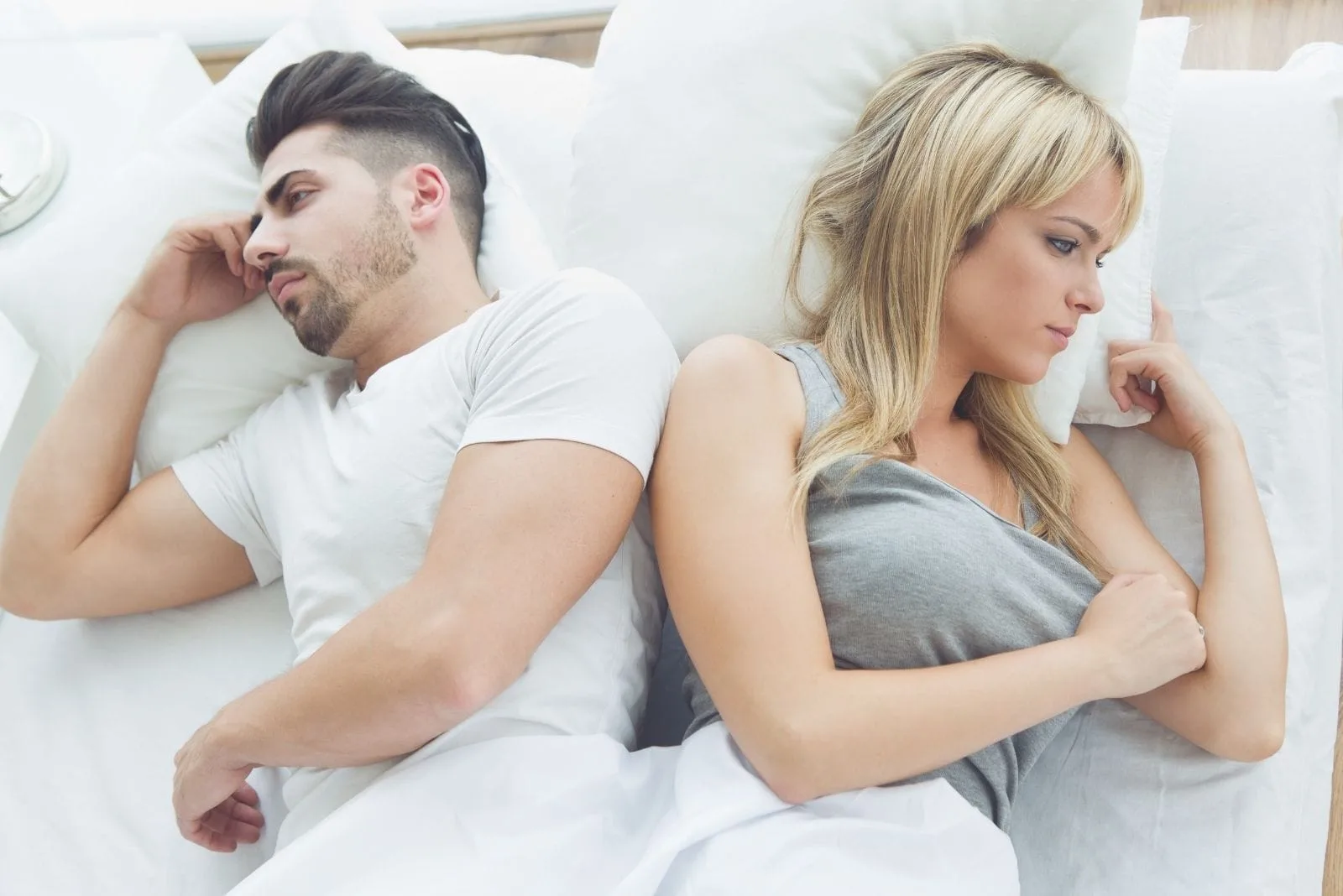 arguing couple in bed facing away from each other